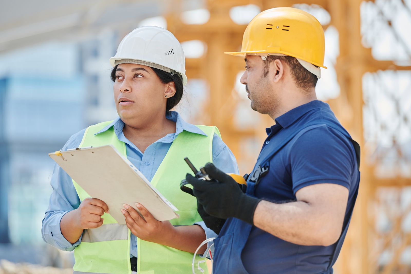 Two colleagues in hard hats reviewing a checklist on site